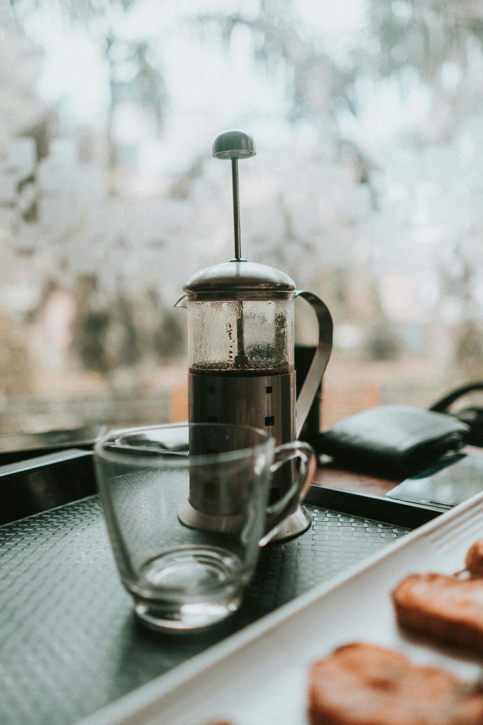 French press coffee and glass cup on a tray, evoking a cozy morning vibe.